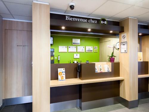 a welcome desk in a hospital lobby with a green wall at B&B HOTEL Montpellier Centre Le Millénaire in Montpellier