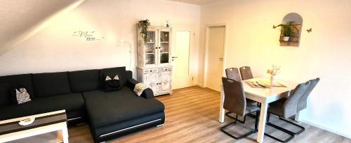 a living room with a black couch and a table at "Deichgraf-Burhave" in Burhave