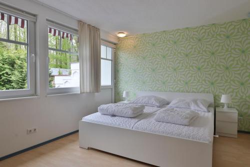 Bungalow Leuchtturm im Ostseeidyll am Waldrand في أوستسيباد نينهاجن: غرفة نوم بسرير ابيض بجدار اخضر