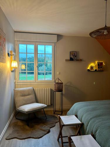 a bedroom with a bed and a chair and a window at Maison la belle vue in Nogent-le-Rotrou