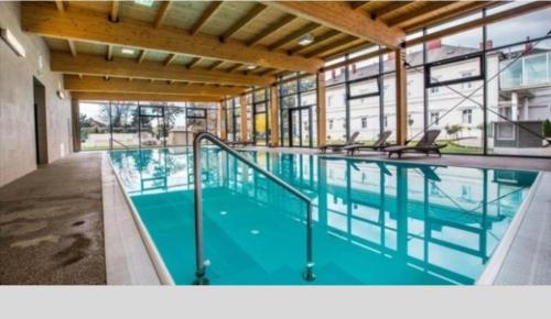 a large swimming pool with blue water in a building at Apartmán PARK in Piešťany