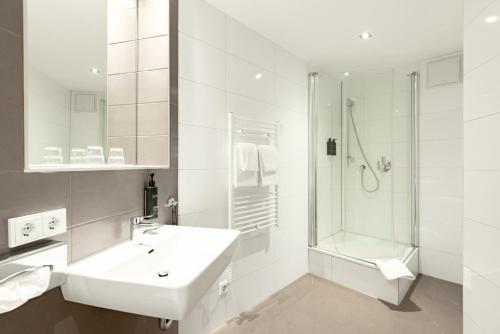 ein weißes Badezimmer mit Waschbecken und Dusche in der Unterkunft Garner Hotel Dusseldorf - Main Station by IHG in Düsseldorf
