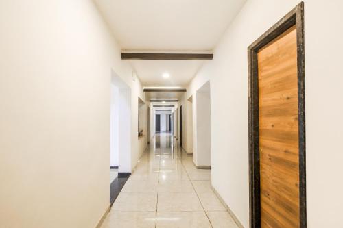 a hallway with white walls and a wooden door at Hotel O Meridian in Bijāpur