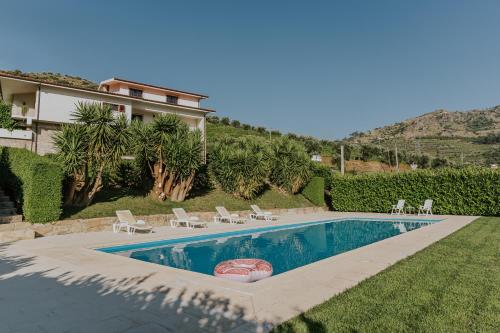a swimming pool with chairs and a house at Jerónimos Garden & Pool Villas in Lamego