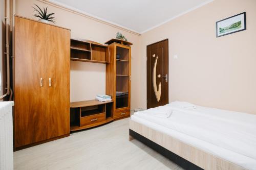 a bedroom with a bed and a wooden cabinet at B-G Apartments in Gheorgheni