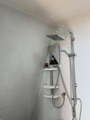 a shower with a shower head and a shelf at Leesuma Homestay in Ban San Pu Loei