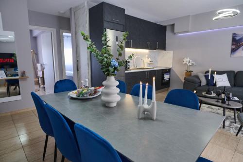a dining table with blue chairs and a vase with flowers at V & S Downtown Apartment AXD in Alexandroupoli