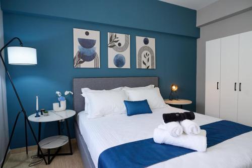 a bedroom with blue walls and a bed with towels at V & S Downtown Apartment AXD in Alexandroupoli