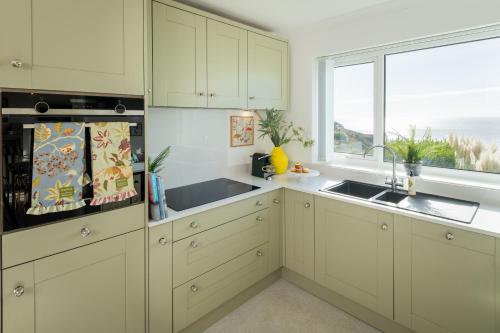 a kitchen with white cabinets and a large window at NEW Luxury Beachfront House sleeps 8 Exmouth Devon in Exmouth