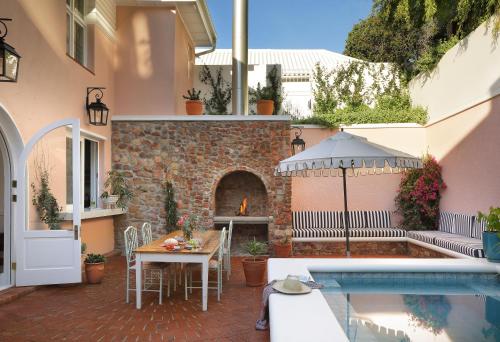 Un patio con una mesa y una piscina. en Hillside House, en Fish Hoek