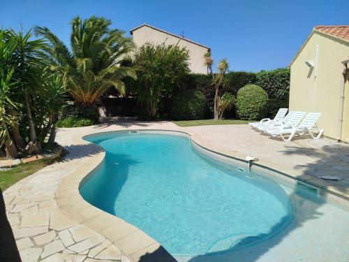a swimming pool in a yard with two chairs at Superbe villa T4 classée 3 étoiles avec piscine privative chauffée 8PALCR in Saint Cyprien Plage