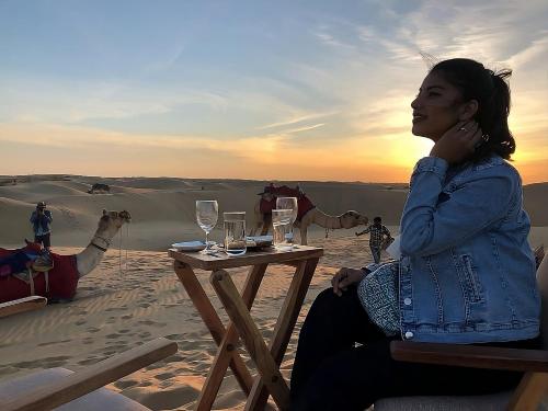 uma mulher sentada numa mesa no deserto em Desert Heaven Camp - A Family Luxury Resort Jaisalmer em Jaisalmer