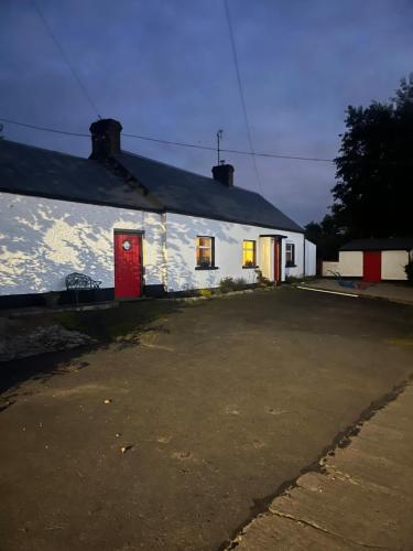 un bâtiment blanc avec une porte rouge et un parking dans l'établissement Campbell's Cottage, à Blackwatertown