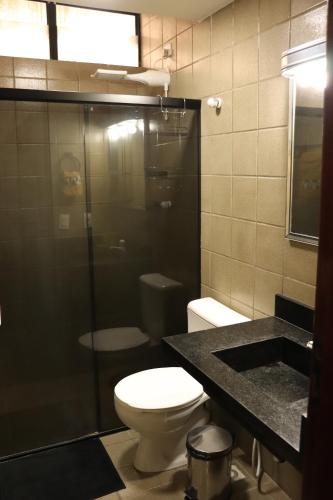 a bathroom with a toilet and a glass shower at Studio na Jatiuca in Maceió