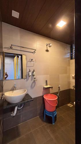 a bathroom with a sink and a red bucket at Balaji Excellency Resort in Mahabaleshwar
