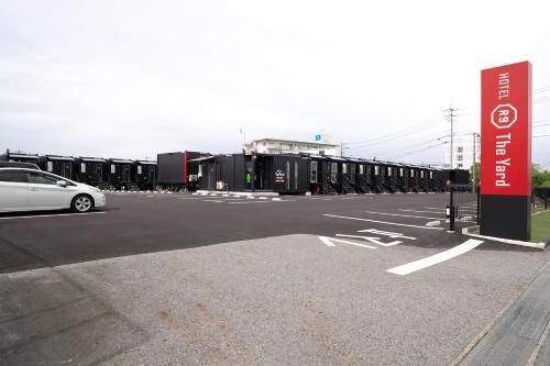 a white car parked in a parking lot with containers at HOTEL R9 The Yard Yamaguchiajisu in Azisu