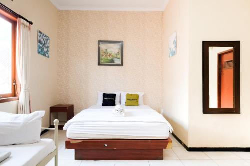 a bedroom with a white bed and a mirror at Urbanview Hotel Griya Surya Malang by RedDoorz in Malang