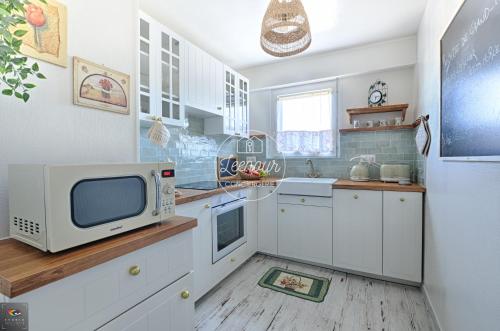 a kitchen with white cabinets and a microwave at Chez Grand-Mère Cozy Retro Apartment in the Heart of Metz in Metz