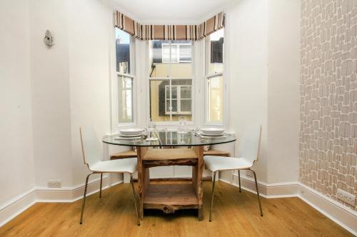 a dining room with a table and chairs and a window at Marine Cottage - Parking - by Brighton Holiday Lets in Brighton & Hove