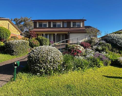 a house with a bunch of flowers in a yard at Sunny Lakeview Lodge- Perfect for Family & Friends in Bonnells Bay