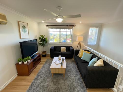a living room with a couch and a tv at Sunny Lakeview Lodge- Perfect for Family & Friends in Bonnells Bay
