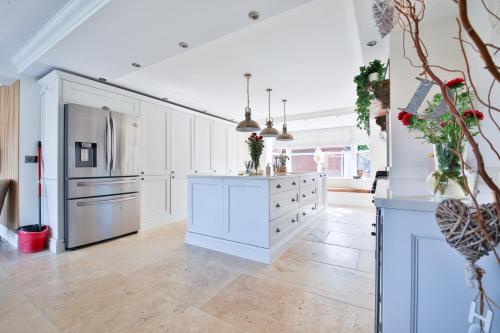 a kitchen with white cabinets and a refrigerator at Modern 5-Bed Retreat with Parking in Cockett