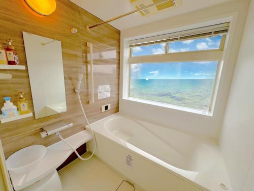 ein Badezimmer mit Badewanne und Waschbecken und einem Fenster in der Unterkunft The feel Kincho cho Seaside villa - sea - / Vacation STAY 26185 in Yaka