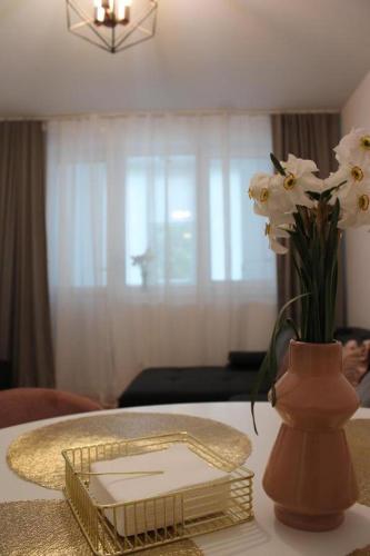 a table with a vase with white flowers in it at The Friendly Apartment in Turda