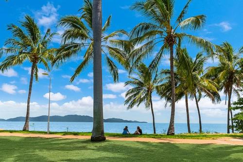 two people sitting under palm trees on the beach at Saltz on The Strand in North Ward