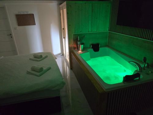 Un baño con bañera verde y una cama. en Room with jacuzzi and sauna Edy, en Zagreb