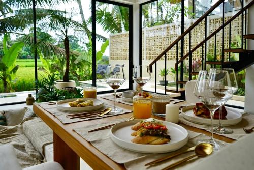 een tafel met borden met eten en glazen wijn bij Ubud Dzen Villa 4 in Ubud