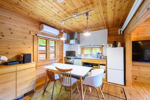 a kitchen with wooden walls and a table and chairs at The Lodge Teshikaga in Teshikaga