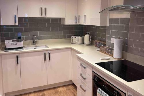 a kitchen with white cabinets and black appliances at 2 Bed Cottage - Sleeps 4 - Parking - Wifi in Bridgnorth