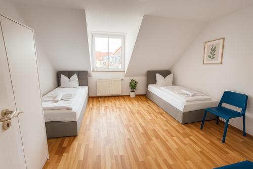 ein kleines Zimmer mit zwei Betten und einem blauen Stuhl in der Unterkunft SUNNYHOME Monteurwohnungen und Apartments in Schwandorf in Schwandorf in Bayern