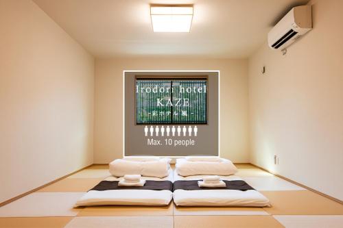 two beds in a room with a painting on the wall at Irodori Hotel KAZE in Fukuoka