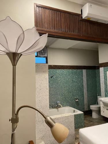 a lamp in a bathroom with a tub and a sink at Margot Guest House in Sanur
