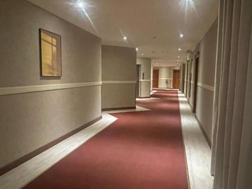 an empty hallway with a red carpet in a building at Wakra Inn Hotel Apartments in Al Wakrah