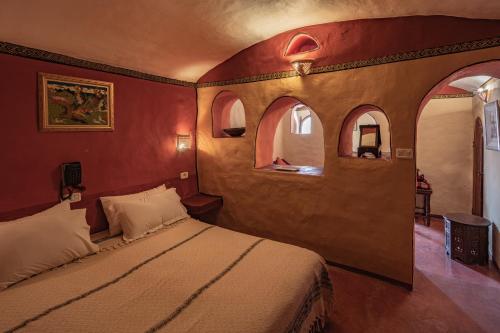 a bedroom with a bed with red walls and arched windows at Ksar Ouled Debbab 