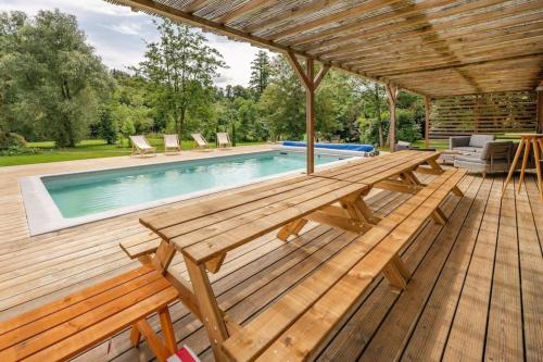 a wooden deck with a picnic table and a swimming pool at La Dommarienne - Collection Idylliq in Dommiers