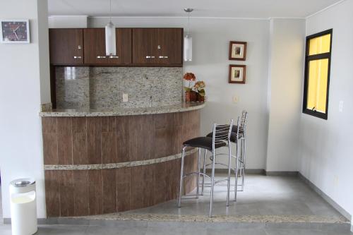 a kitchen with a bar with stools in it at Paradise Hotel in Campo Grande