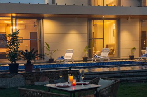 a patio with a table and chairs and a pool at SaffronStays Raaga - luxury 4BR villa with private pool, lawns, gazebos & sweeping Aravalli hill views in Udaipur