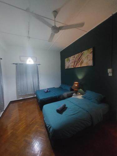 a bedroom with two beds and a ceiling fan at A Borneo Guesthouse in Johor Bahru