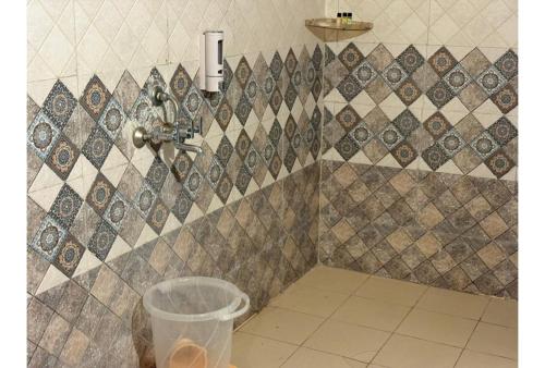 a bathroom with a tiled wall with a trash can at Shikaar Valley in Khilchipur