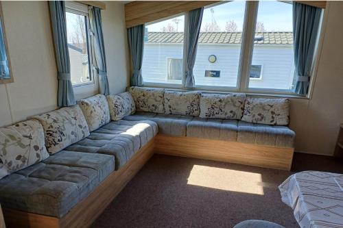 a large couch in a room with two windows at 3 Bedroom Caravan - Sleeps 8 Parking Pets Beach in Hastings