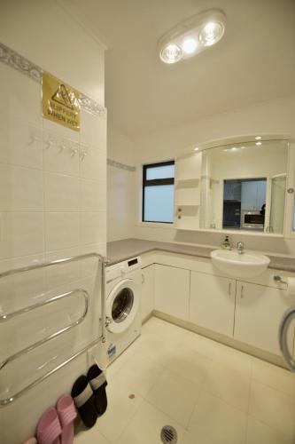 a bathroom with a washing machine and a sink at Family Friendly 1BR in Howick, Near Beach and Cafes in Auckland