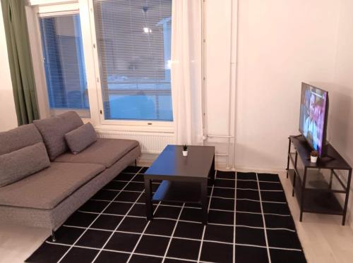 a living room with a couch and a table and a tv at Kotimaailma Apartments - kolmio Espoon keskuksessa in Espoo