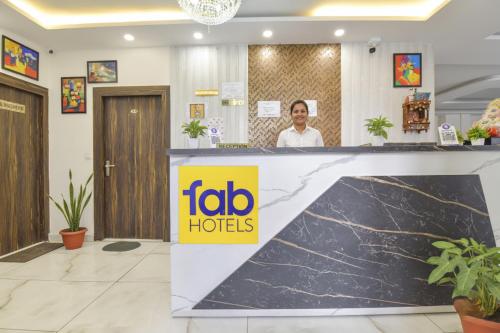 ハリドワールにあるFabHotel Dev Palaceのロビーのフロントデスクの後ろに立つ男