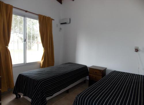 een kamer met twee bedden en een raam bij Las Casitas de Pepin in Santa Rosa de Calamuchita