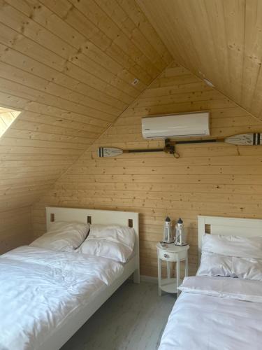 a bedroom with two beds in a wooden room at Domki nad jeziorami Niedźwiady in Ślesin