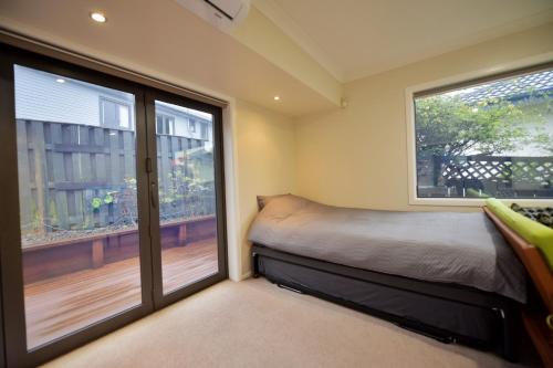a bedroom with a bed and two large windows at Family Friendly 1BR in Howick, Near Beach and Cafes in Auckland